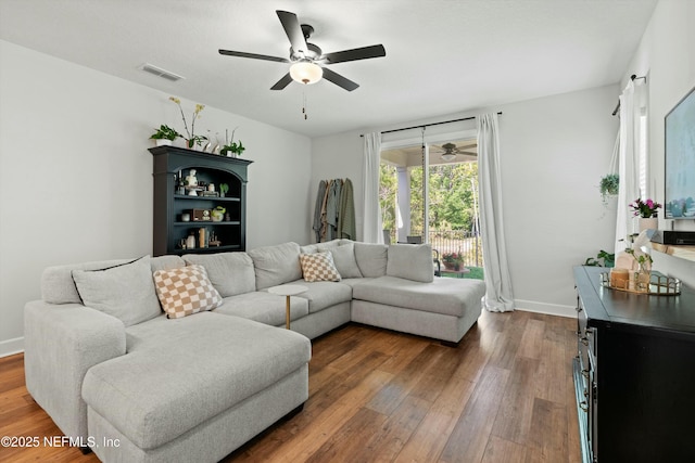 living room with baseboards, ceiling fan, visible vents, and dark wood-type flooring