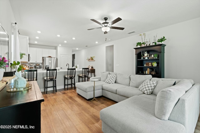 living area featuring light wood-style flooring, visible vents, ceiling fan, and recessed lighting