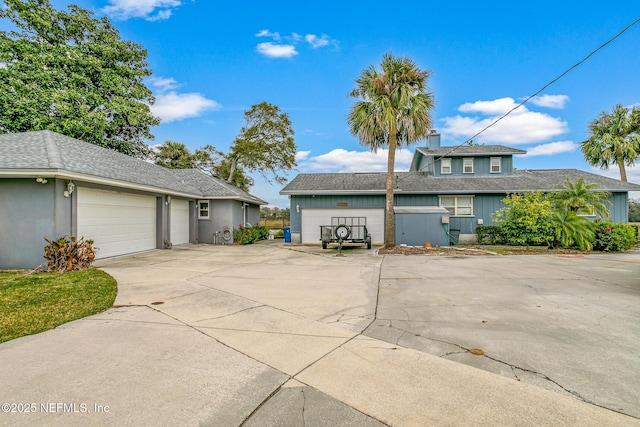 exterior space featuring concrete driveway, a shingled roof, and an attached garage