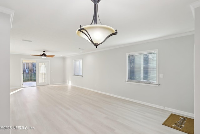 empty room with baseboards, light wood-style floors, and crown molding