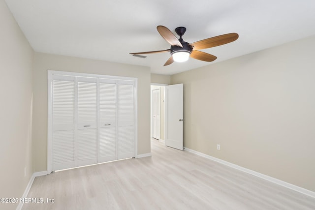 unfurnished bedroom featuring light wood-type flooring, visible vents, baseboards, and a closet