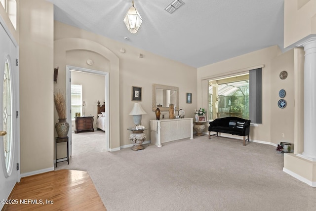 entrance foyer with carpet floors, visible vents, decorative columns, and baseboards