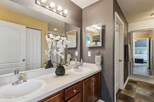 bathroom featuring a textured ceiling, double vanity, a closet, and a sink