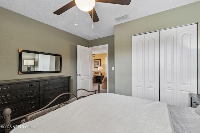 bedroom featuring a ceiling fan, a closet, visible vents, and a textured ceiling