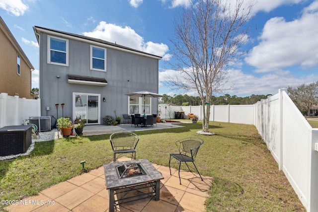 back of property featuring a patio area, a fenced backyard, a fire pit, and a lawn