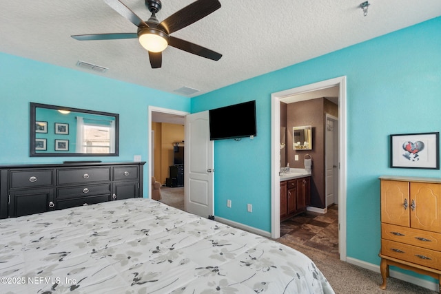 carpeted bedroom with visible vents, connected bathroom, ceiling fan, a textured ceiling, and baseboards