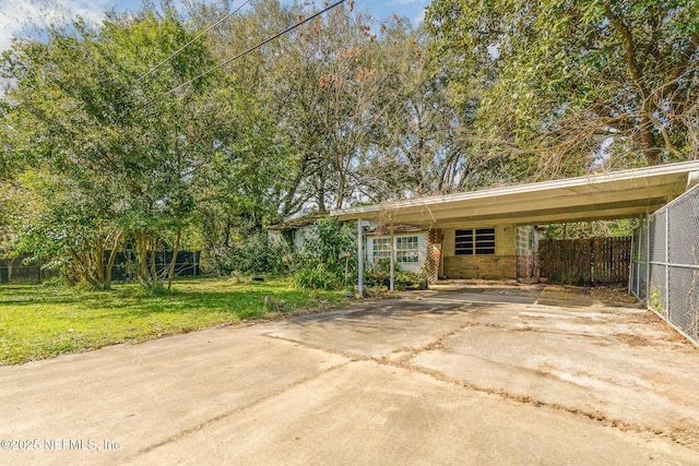 view of front of house with a carport, fence, a front lawn, and concrete driveway