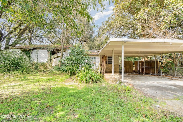 view of front of home with a carport, driveway, a front lawn, and fence