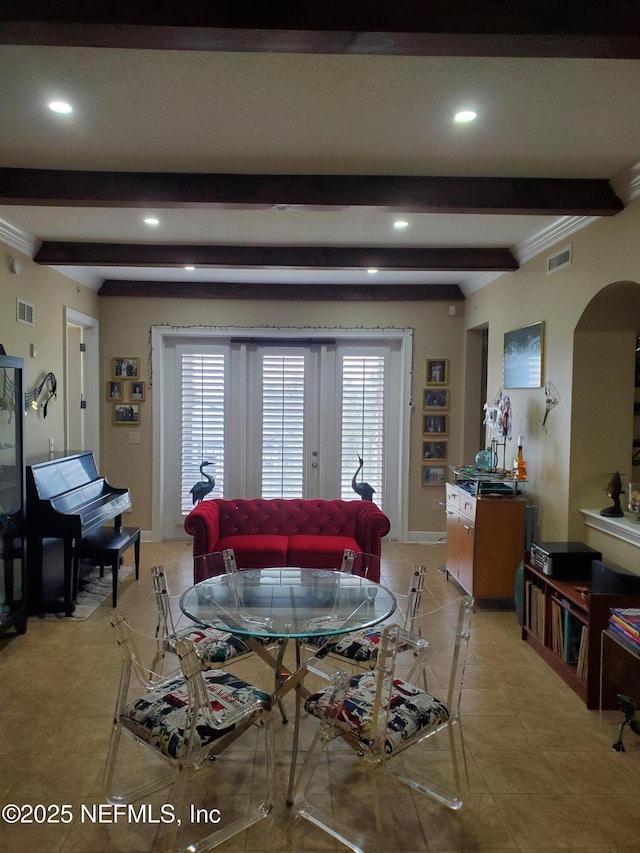 living room with beamed ceiling, arched walkways, visible vents, and a healthy amount of sunlight