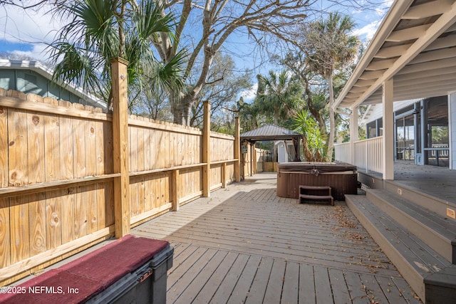 deck with a hot tub, a fenced backyard, and a gazebo