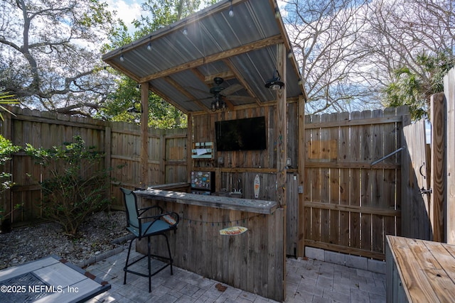 view of patio with outdoor dry bar, fence, and a ceiling fan