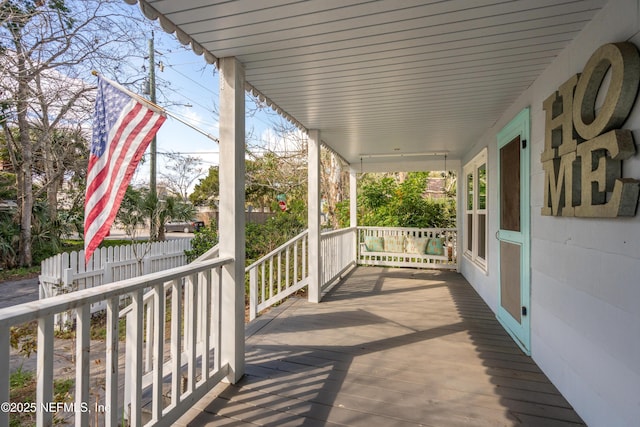 wooden terrace featuring a porch and fence