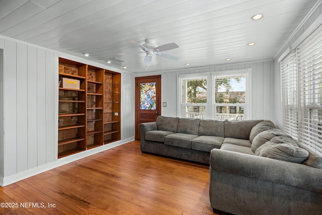 living room with built in shelves, recessed lighting, ornamental molding, and wood finished floors