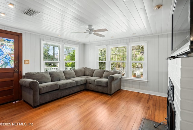 living room featuring plenty of natural light, a fireplace with flush hearth, visible vents, and wood finished floors