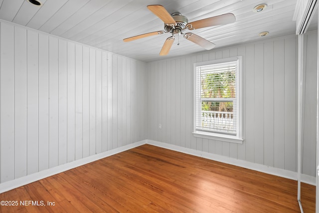 empty room featuring ceiling fan, baseboards, and wood finished floors