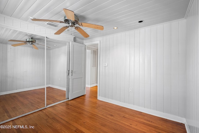 unfurnished bedroom with a closet, ceiling fan, baseboards, and wood finished floors