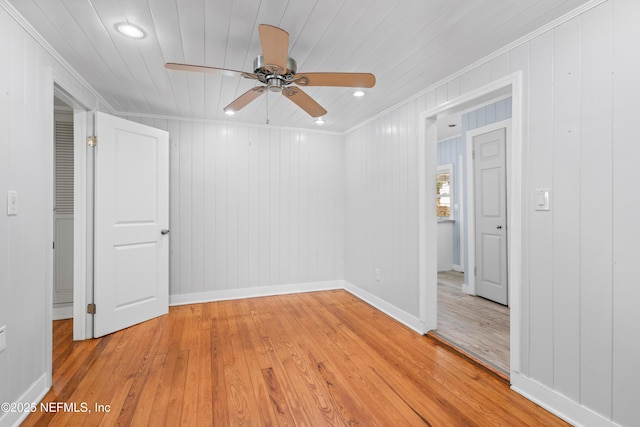 spare room with ornamental molding, light wood finished floors, and baseboards