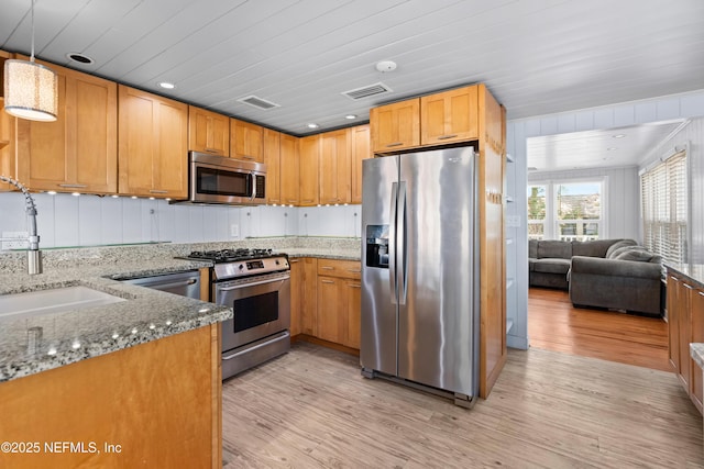 kitchen featuring appliances with stainless steel finishes, open floor plan, visible vents, and light stone countertops