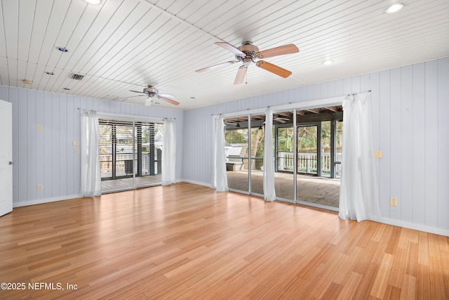 empty room with light wood-type flooring, wooden ceiling, visible vents, and baseboards