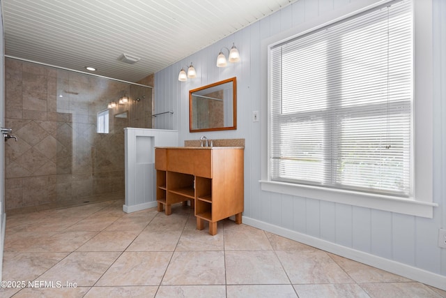 full bathroom with baseboards, tiled shower, vanity, and tile patterned floors