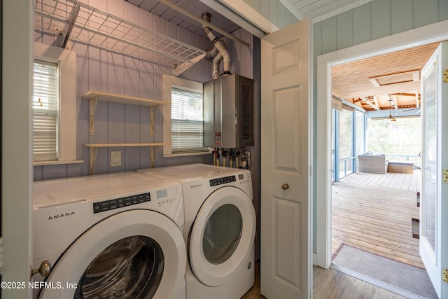 laundry area featuring laundry area, wooden walls, washer and clothes dryer, light wood-style flooring, and water heater