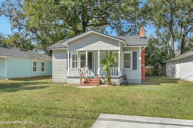 bungalow-style house featuring covered porch, a shingled roof, a chimney, and a front yard