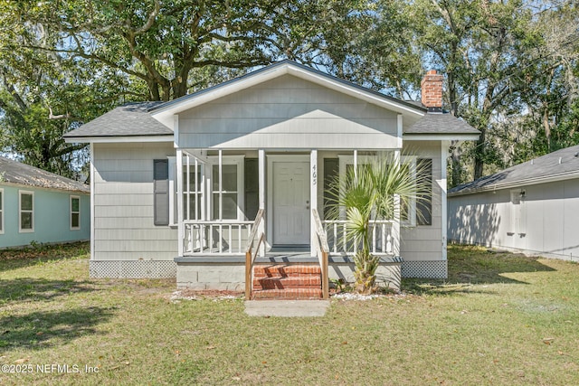 bungalow-style house featuring a front lawn, a chimney, a shingled roof, and a sunroom