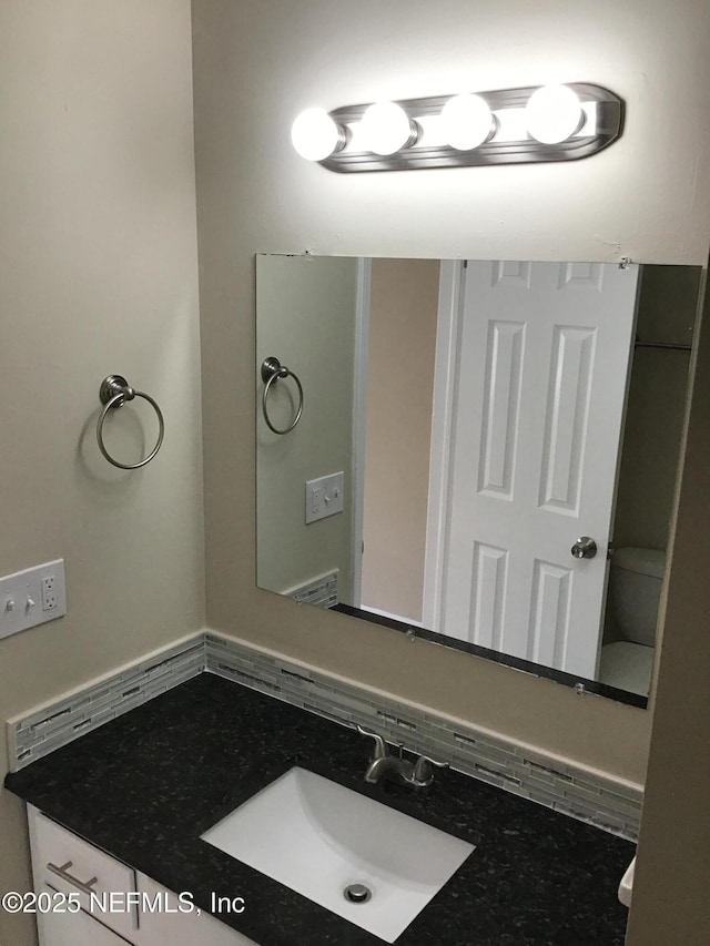 bathroom featuring toilet, vanity, and decorative backsplash