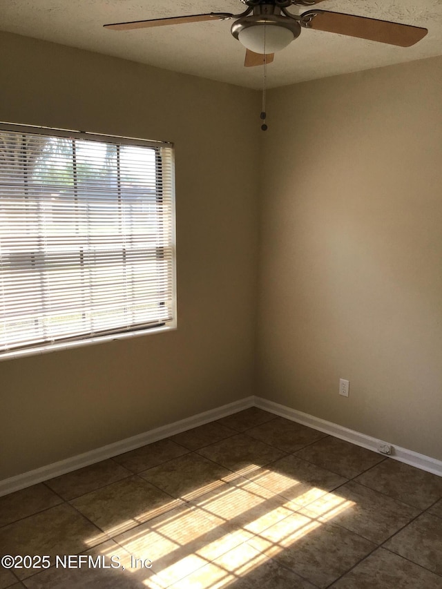 unfurnished room with ceiling fan, tile patterned floors, and baseboards