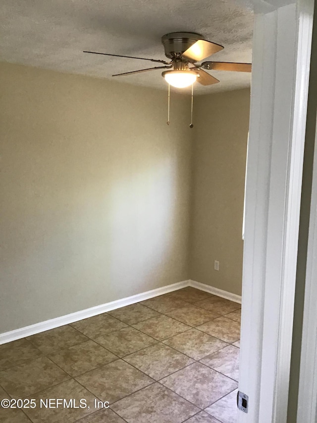 spare room with ceiling fan, a textured ceiling, and baseboards