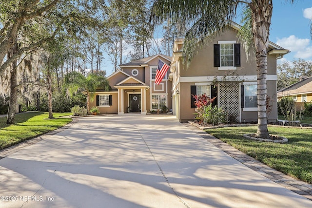 traditional home featuring driveway, a front lawn, and stucco siding