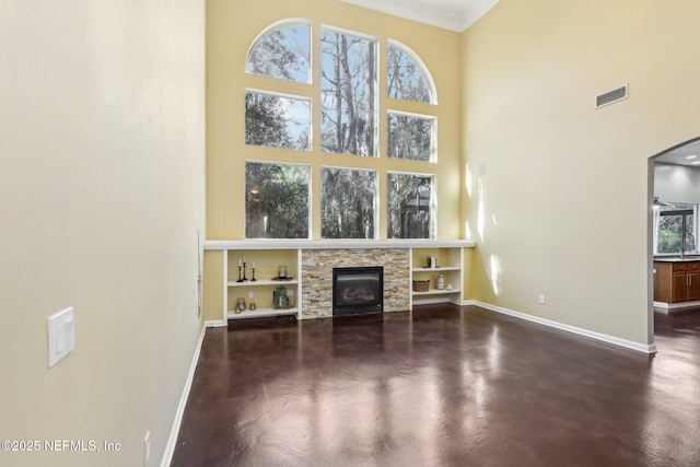 unfurnished living room with finished concrete floors, visible vents, a stone fireplace, and baseboards