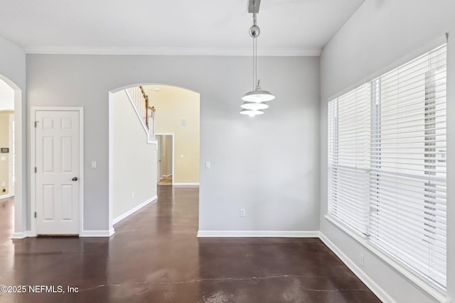 unfurnished dining area with baseboards, arched walkways, concrete flooring, and a wealth of natural light