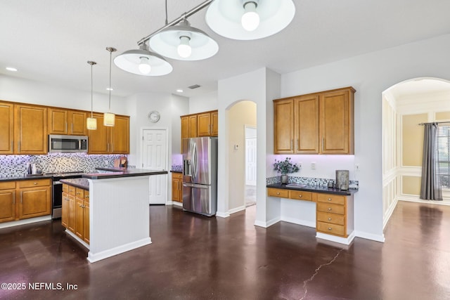 kitchen featuring stainless steel appliances, concrete floors, brown cabinets, decorative backsplash, and dark countertops