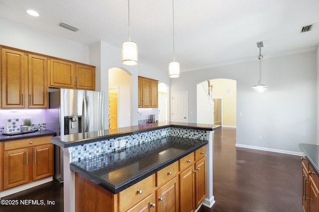 kitchen featuring arched walkways, brown cabinetry, a kitchen island, and visible vents