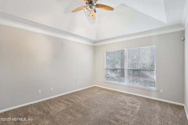 carpeted spare room with baseboards, ceiling fan, ornamental molding, a tray ceiling, and vaulted ceiling