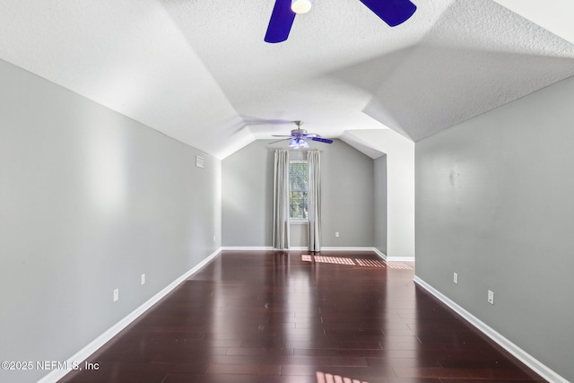 additional living space featuring lofted ceiling, ceiling fan, a textured ceiling, wood finished floors, and baseboards