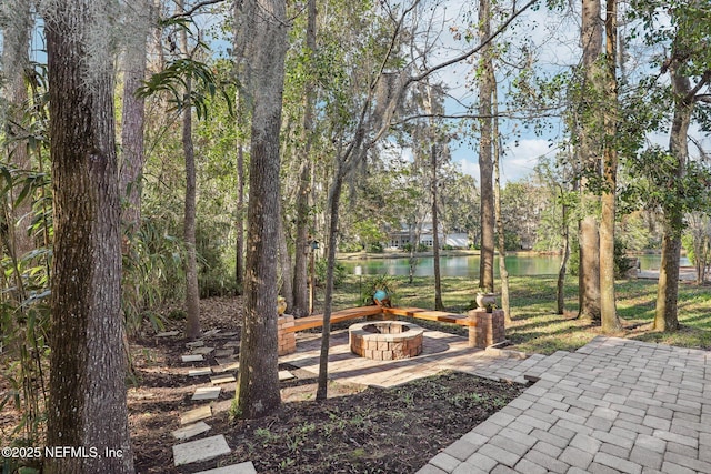 view of yard featuring a fire pit, a patio area, and a water view