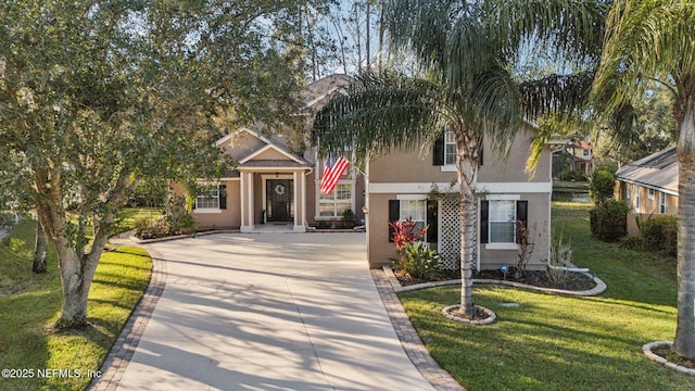 view of front facade featuring a front yard, concrete driveway, and stucco siding