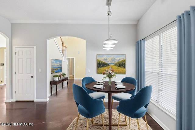 dining room with arched walkways, crown molding, and baseboards