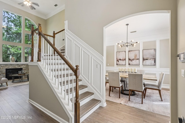 1494 Walnut Creek Dr, Fleming Island, FL 32003 - stairway with wood finished floors, arched walkways, crown molding, a stone fireplace, and a chandelier
