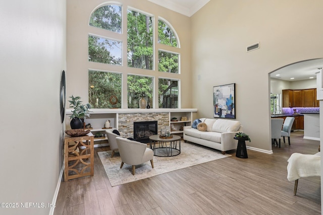 1494 Walnut Creek Dr, Fleming Island, FL 32003 - living area with arched walkways, a high ceiling, wood finished floors, a fireplace, and crown molding