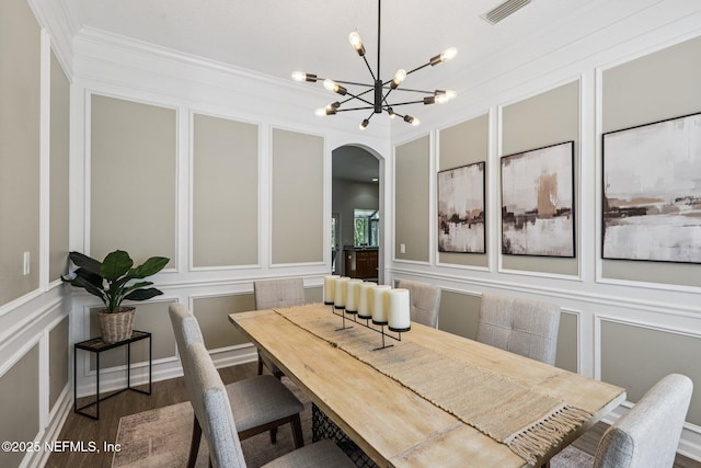 1494 Walnut Creek Dr, Fleming Island, FL 32003 - dining space with a decorative wall, arched walkways, a chandelier, wood finished floors, and crown molding