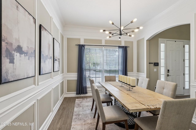 1494 Walnut Creek Dr, Fleming Island, FL 32003 - dining space featuring ornamental molding, arched walkways, wood finished floors, a chandelier, and a decorative wall