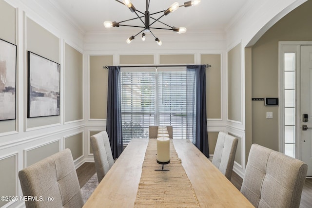 1494 Walnut Creek Dr, Fleming Island, FL 32003 - dining space featuring a chandelier, a decorative wall, arched walkways, wood finished floors, and ornamental molding