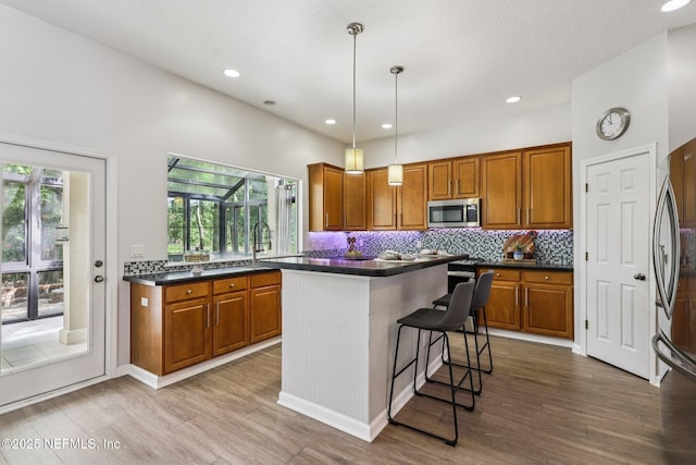 1494 Walnut Creek Dr, Fleming Island, FL 32003 - kitchen featuring appliances with stainless steel finishes, brown cabinets, dark countertops, wood finished floors, and recessed lighting
