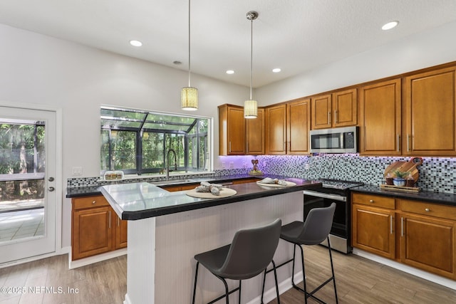 1494 Walnut Creek Dr, Fleming Island, FL 32003 - kitchen with stainless steel appliances, dark countertops, brown cabinetry, decorative backsplash, and a breakfast bar area