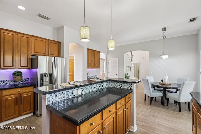1494 Walnut Creek Dr, Fleming Island, FL 32003 - kitchen with arched walkways, light wood finished floors, a center island, and brown cabinetry