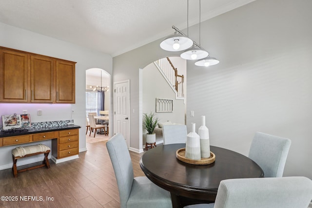 1494 Walnut Creek Dr, Fleming Island, FL 32003 - dining area with dark wood finished floors, arched walkways, ornamental molding, and a chandelier
