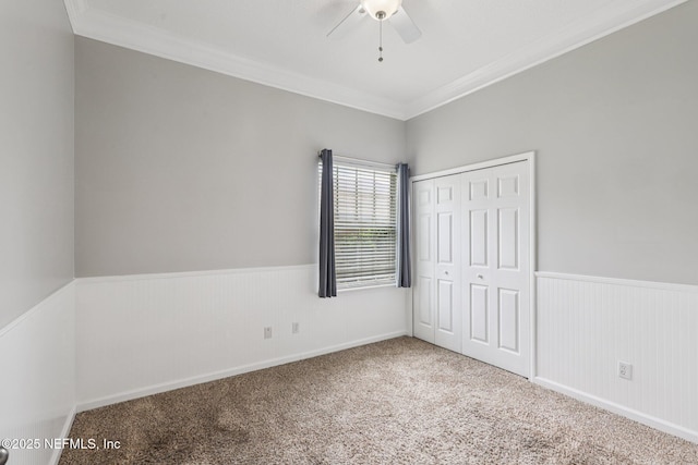 1494 Walnut Creek Dr, Fleming Island, FL 32003 - unfurnished bedroom with crown molding, a wainscoted wall, carpet floors, a closet, and a ceiling fan